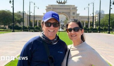 Krista Jucknath Hickman and her husband Mike, both in sunglasses, pose for a photo in front of a decorative archway in Dubai