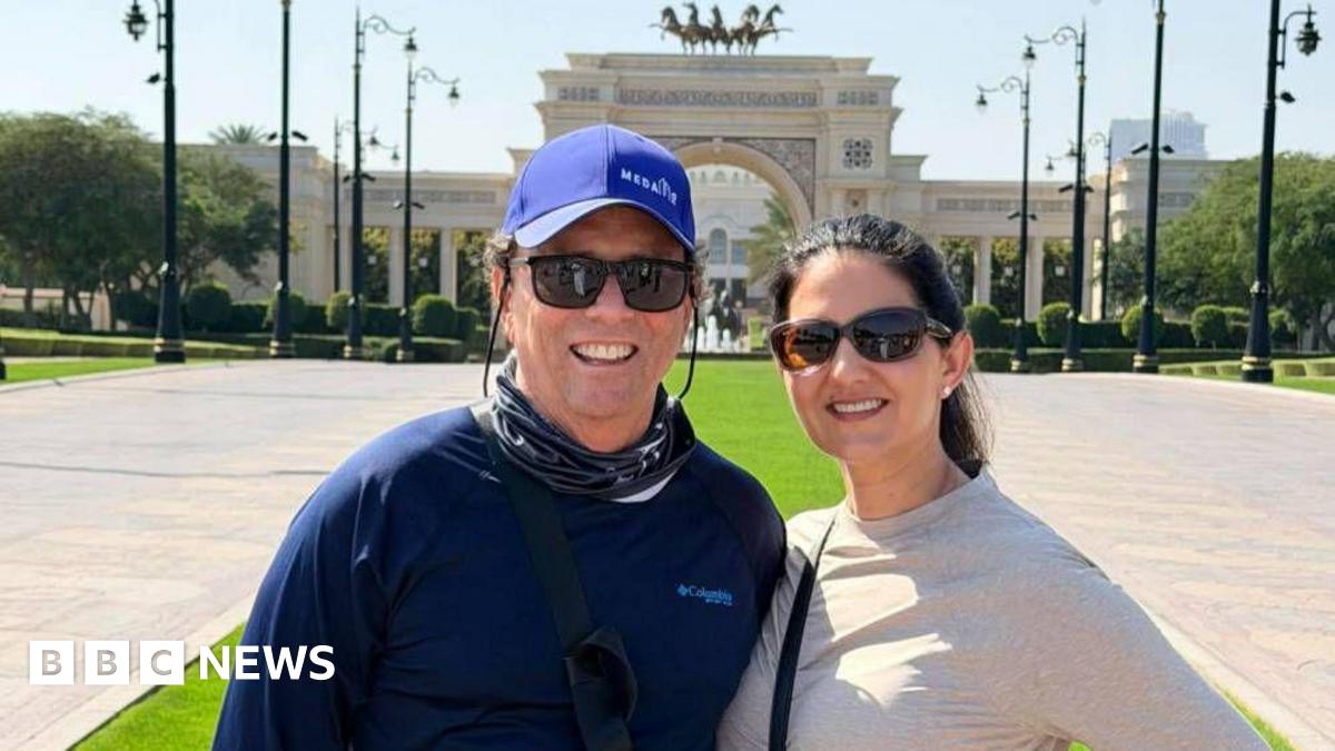 Krista Jucknath Hickman and her husband Mike, both in sunglasses, pose for a photo in front of a decorative archway in Dubai