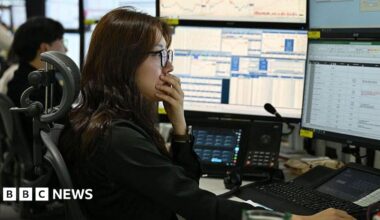 A currency dealer has her hand over her mouth as she and her team monitor exchange rates in a  dealing room at the Hana Bank headquarters in Seoul on 4 March