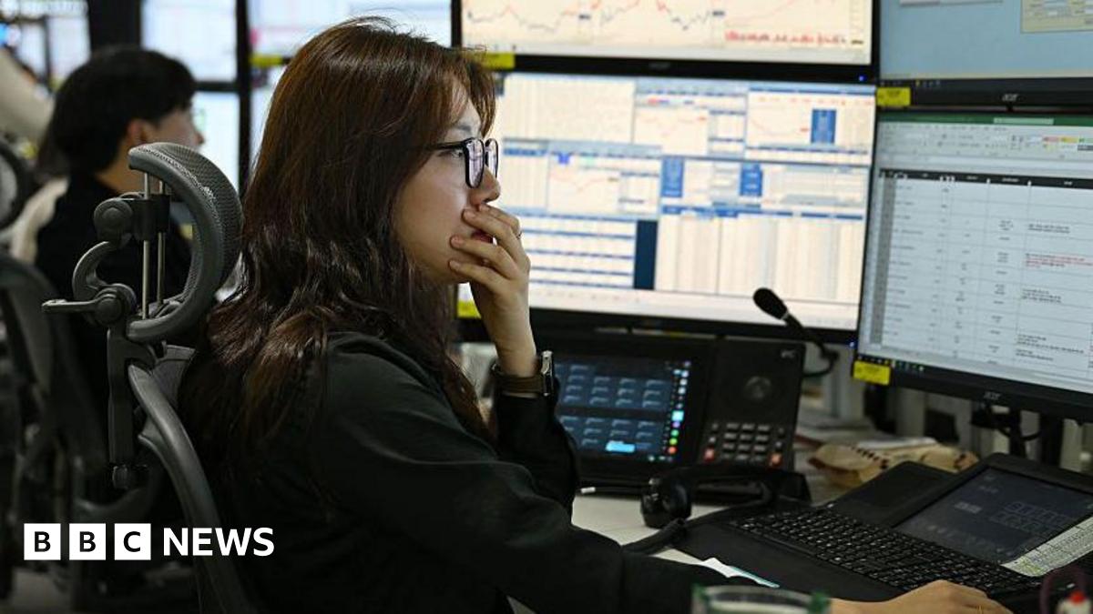 A currency dealer has her hand over her mouth as she and her team monitor exchange rates in a  dealing room at the Hana Bank headquarters in Seoul on 4 March