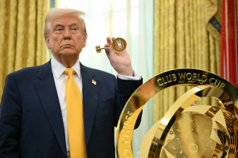Trump holds up a key in front of the FIFA Club Cup Trophy