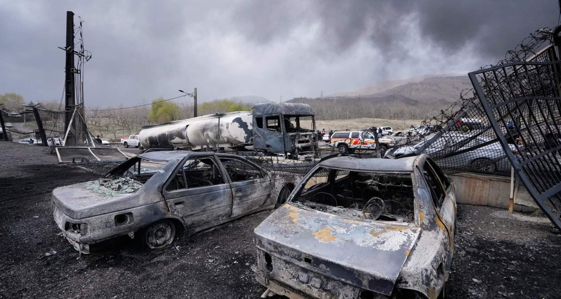 Burned vehicles sit near an oil storage facility struck by a U.S.-Israeli attack late Saturday as a thick plume of smoke rises in Tehran, Iran, Sunday, March 8, 2026. (Vahid Salemi/AP)
