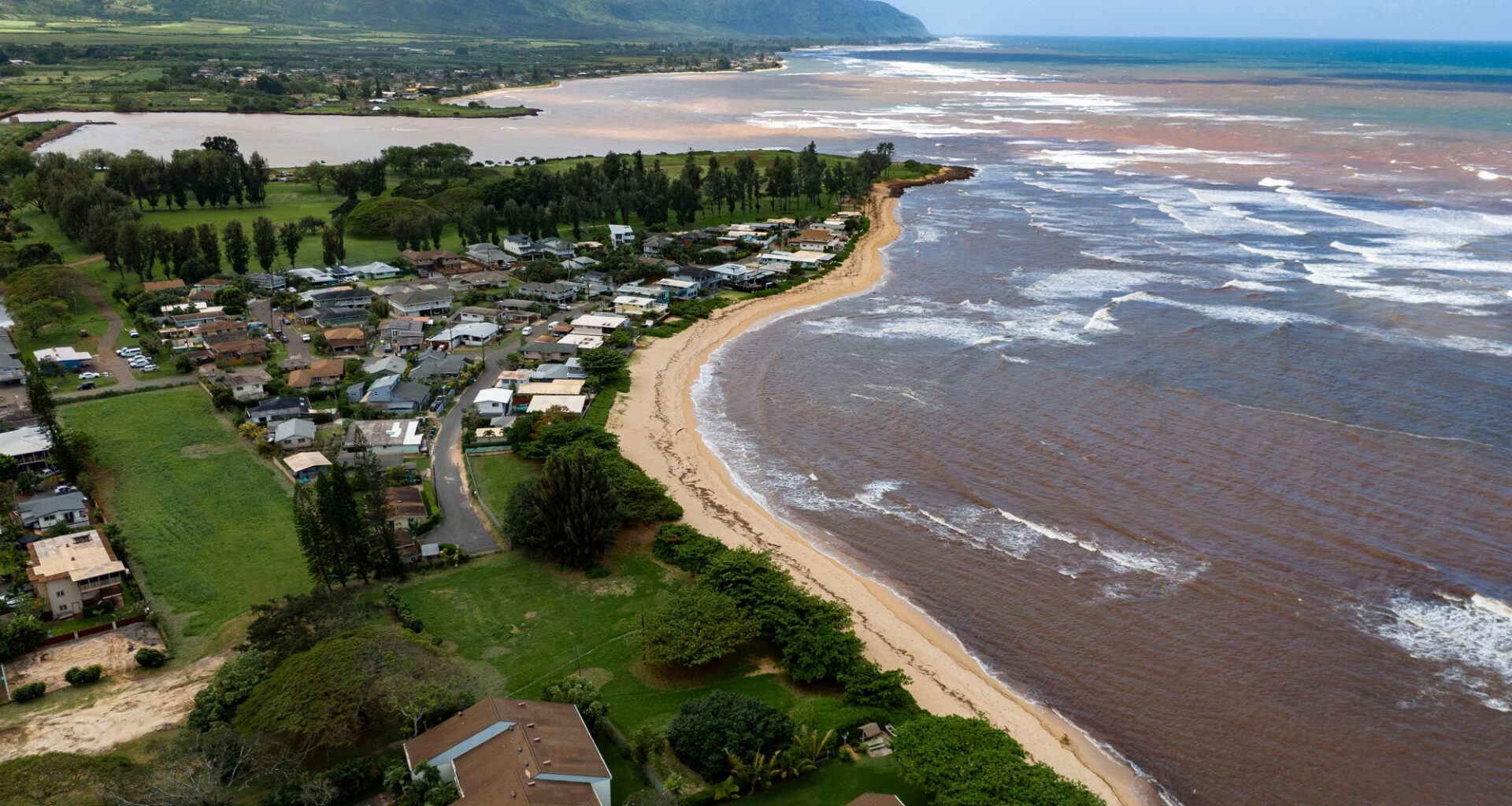 An aerial view shows discolored water along the North Shore coastline, Tuesday, March 24, 2026, in Haleiwa, Hawaii. (AP Photo/Mengshin Lin)