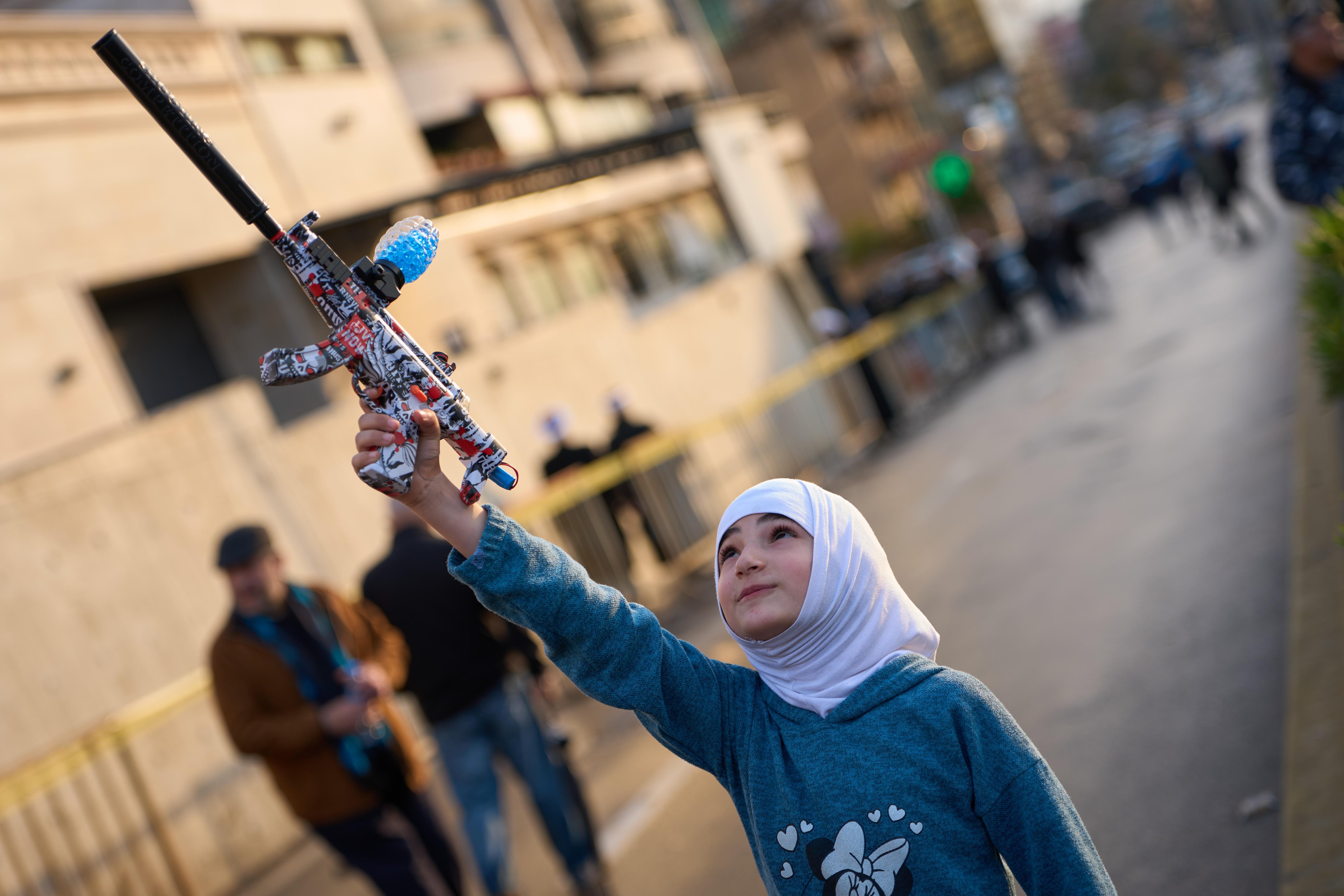 A girl holds a toy gun during a protest outside Iran's embassy.