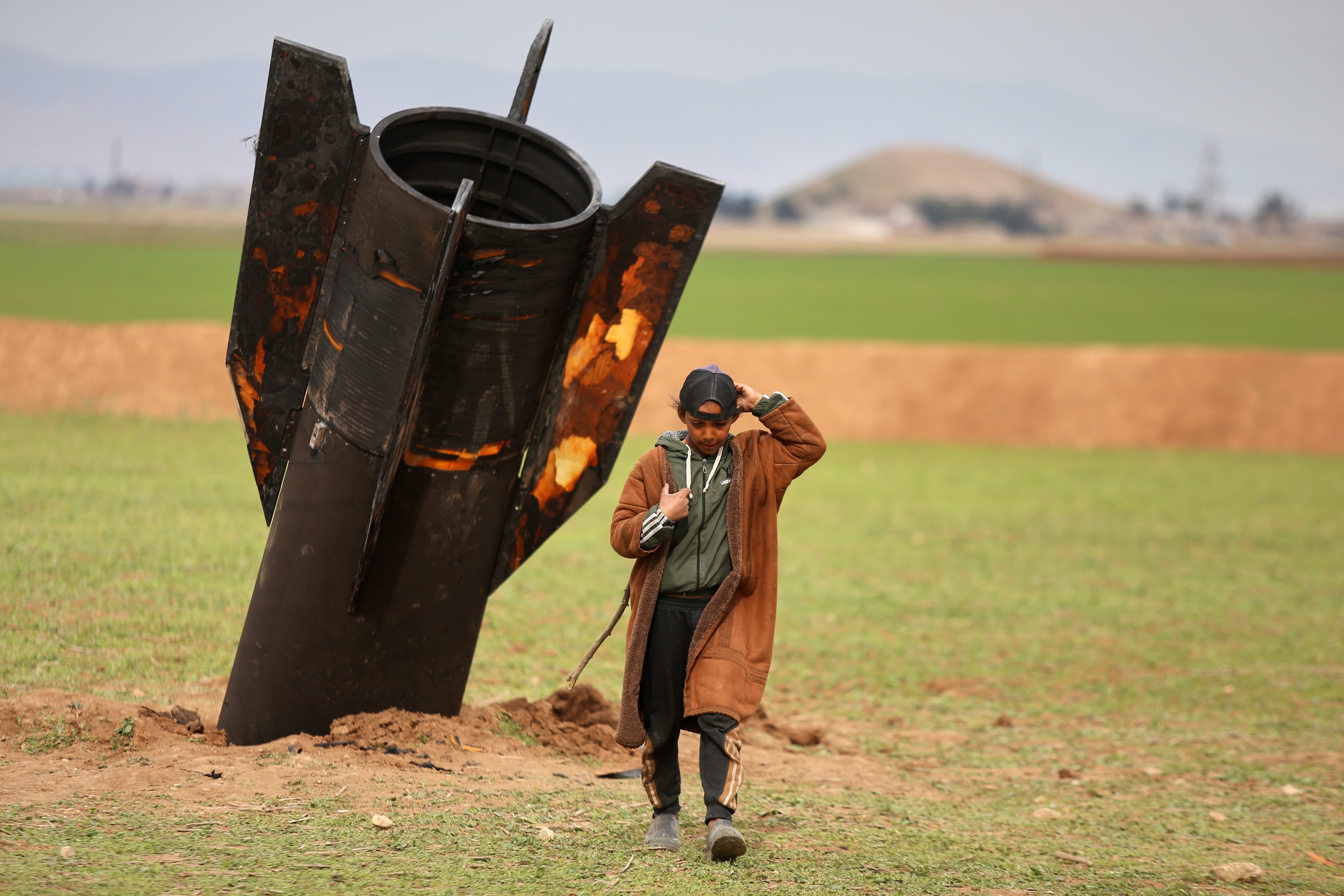 A shepherd boy walks away from an unexploded Iranian missile in Qamishli, eastern Syria