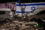 Israeli authorities hang Israeli and U.S. flags at the site struck by an Iranian missile that killed two people, in Ramat Gan, Israel, Wednesday, March 18, 2026.