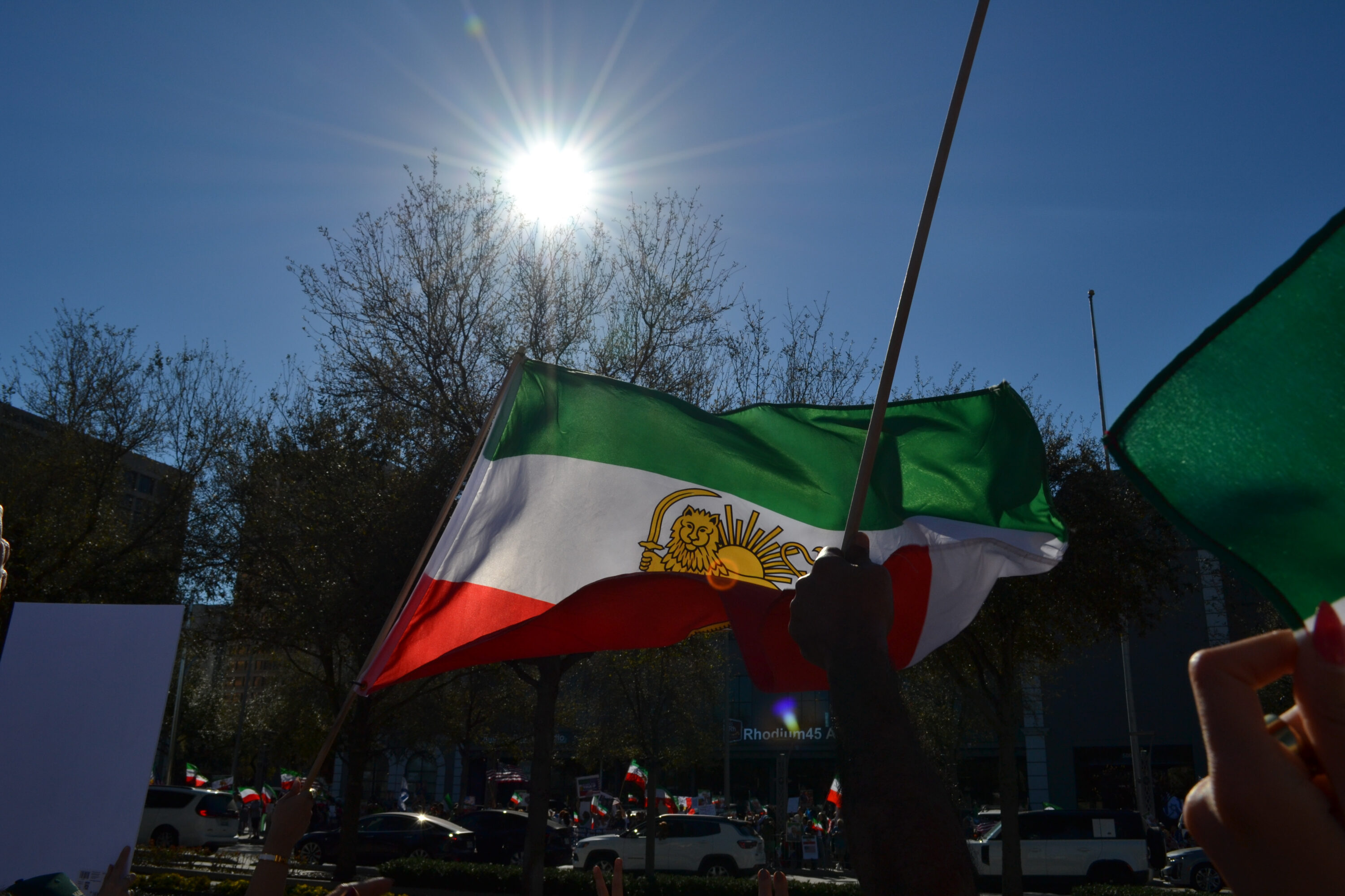 A demonstrator waves an Iranian Lion and Sun flag at a demonstration in Houston celebrating the death of Ayatollah Ali Khamenei.