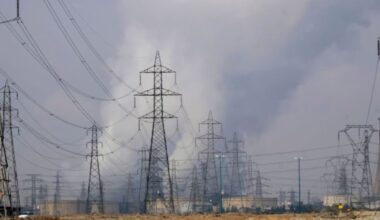 A view of a thermal power station (R) as electricity towers are seen in Malard county, about 60 km (37 miles) north west of Tehran. Photo by Morteza Nikoubazl/NurPhoto via Getty Images.
