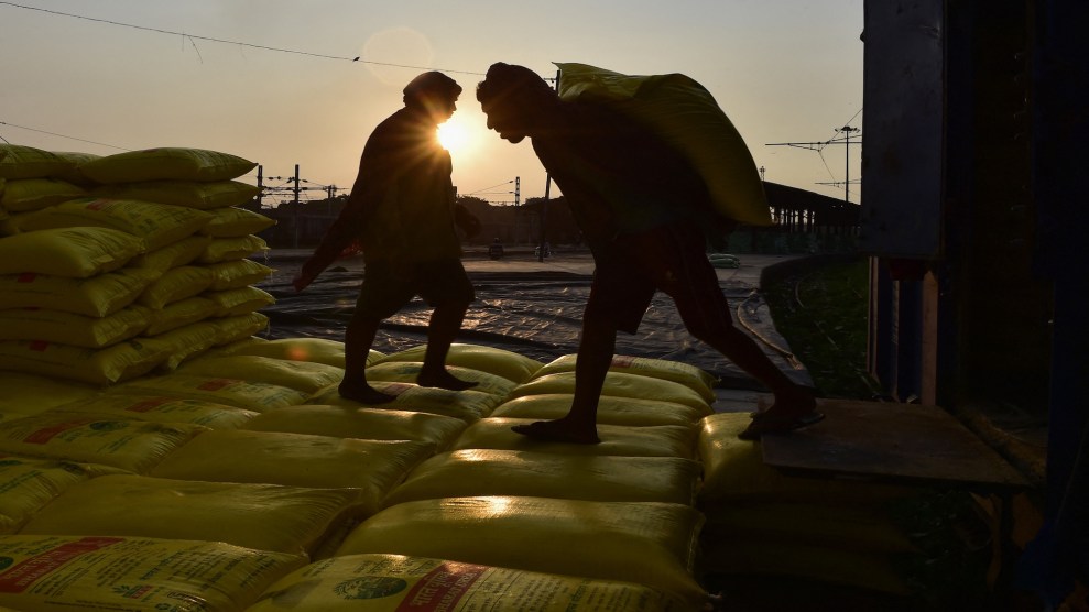 A worker carries a yellow sack of compost on his back.