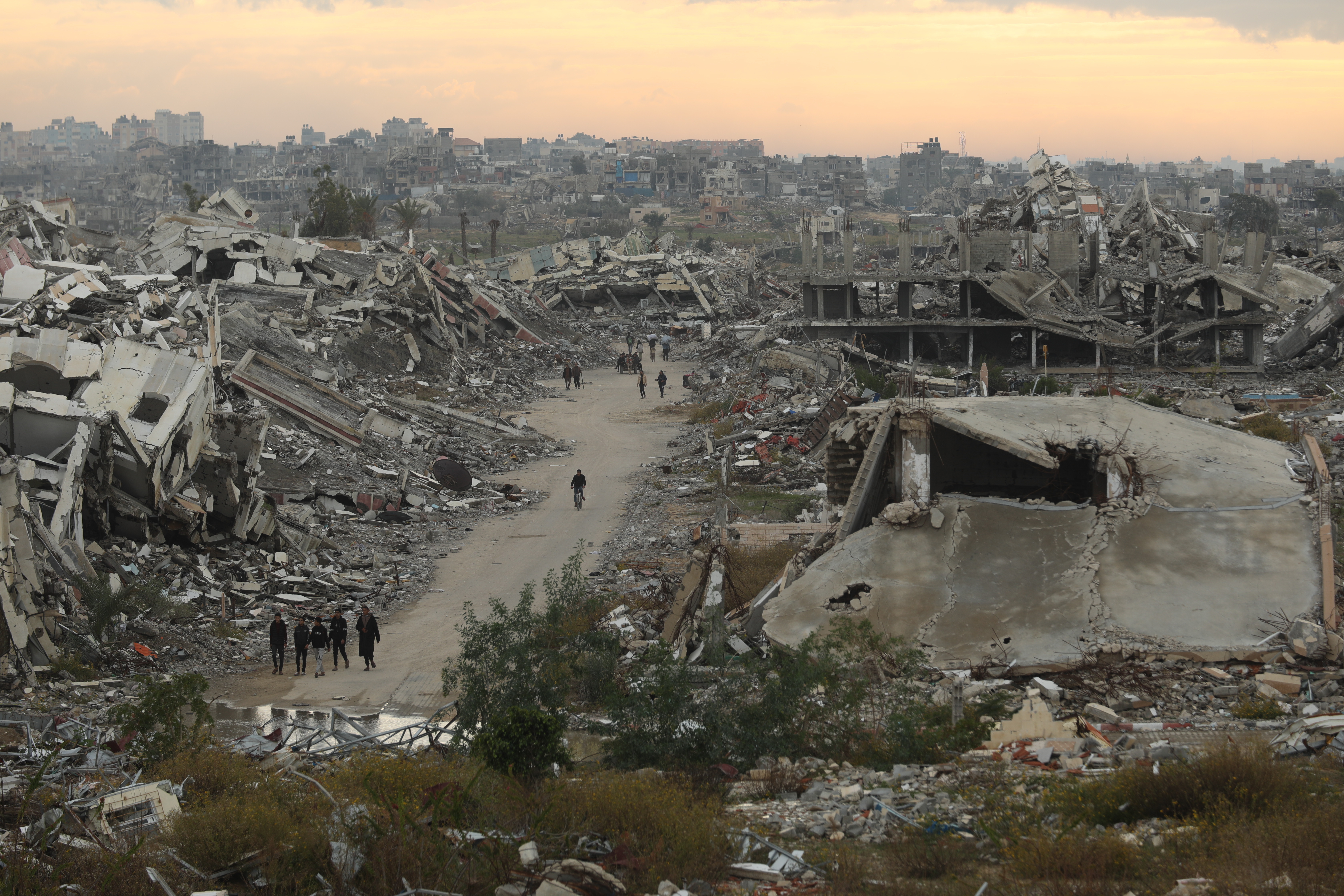 GAZA CITY, GAZA â" DECEMBER 19: Palestinians walk through roads surrounded by massive rubble and collapsed buildings in Al-Zahra, northwest of the Nuseirat Refugee Camp in the central Gaza Strip, as residents continue their daily lives amid the destruction left by Israeli attacks, facing harsh living conditions on December 19, 2025. (Photo by Hassan Jedi/Anadolu via Getty Images)