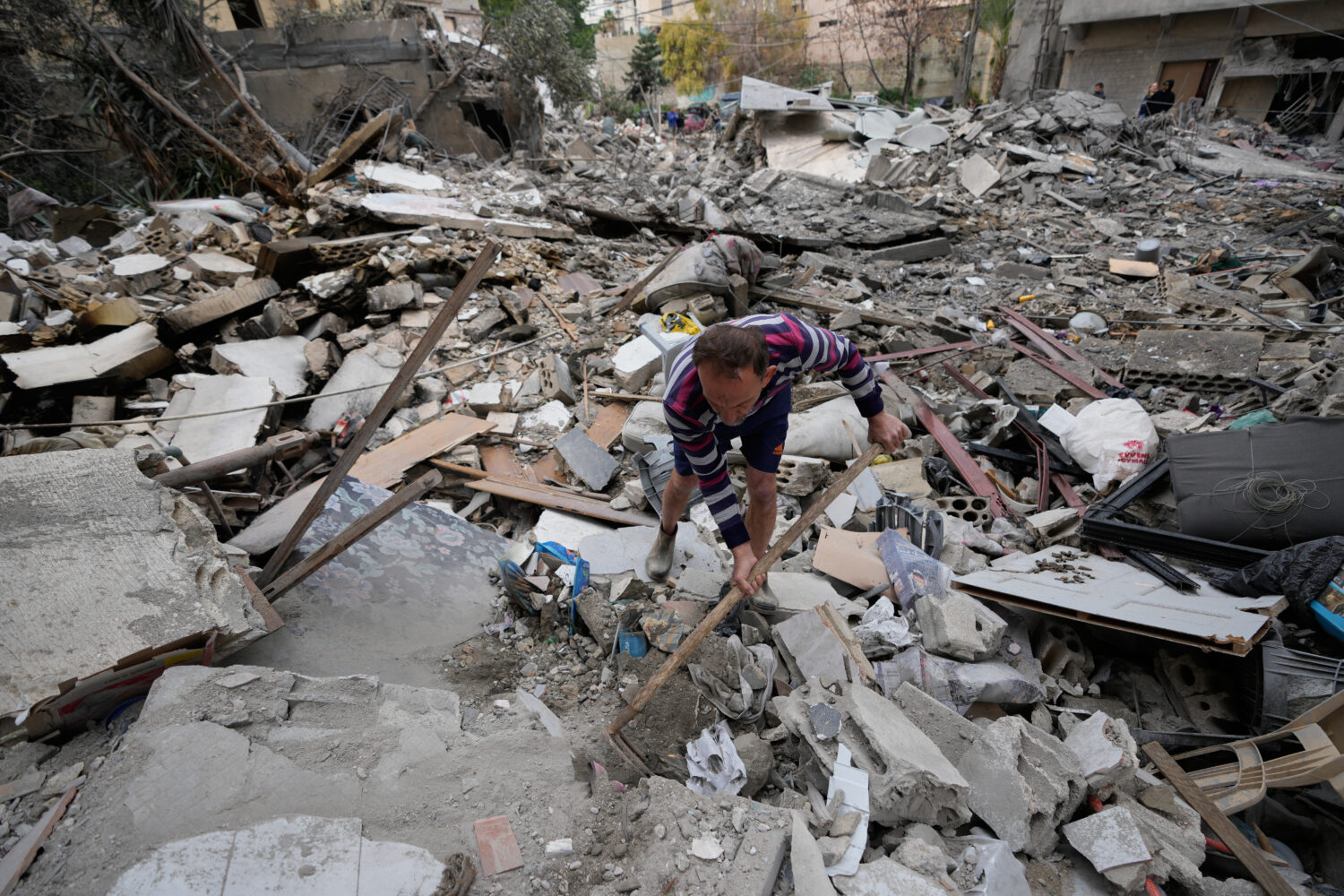 A man removes rubbles as he looks for missed stuff from his destroyed house that was hit in an Isra...