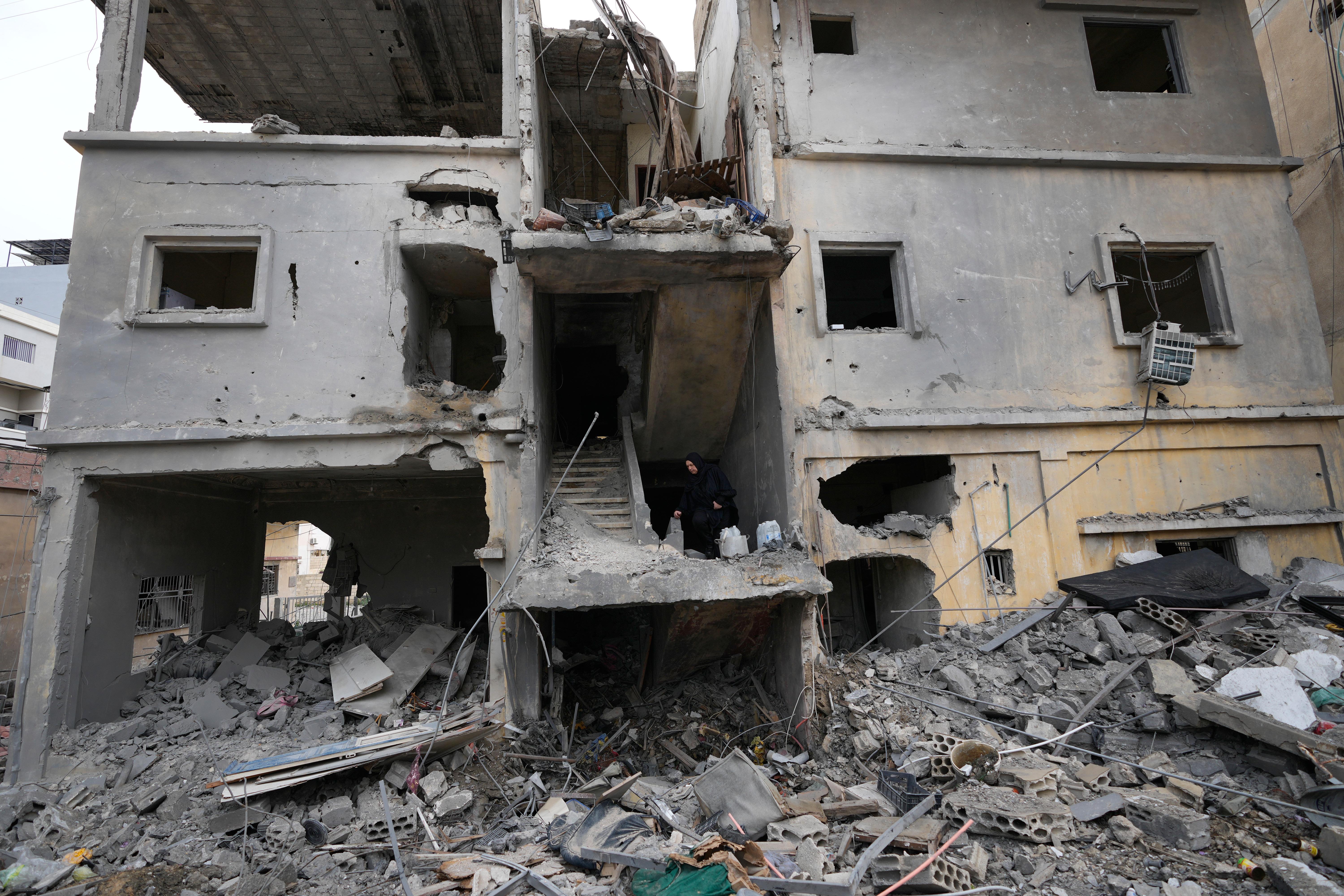 A woman takes the stairs on a destroyed building that...