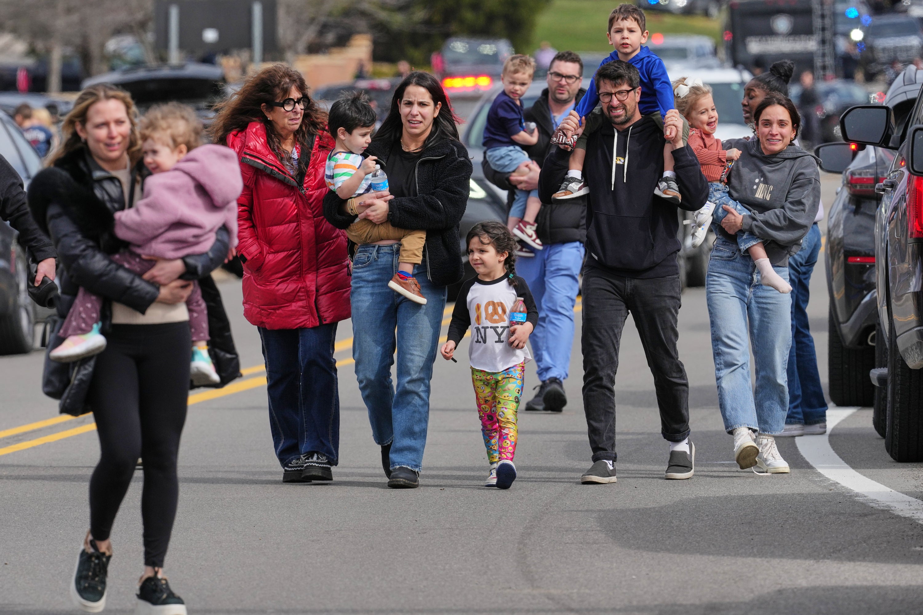 Law enforcement escort families with children away from the Temple Israel synagogue