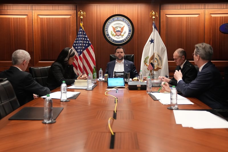 JD Vance sitting at the head of a table in a wood-lined room with his seal and Tulsi Gabbard and Scott Bessent.