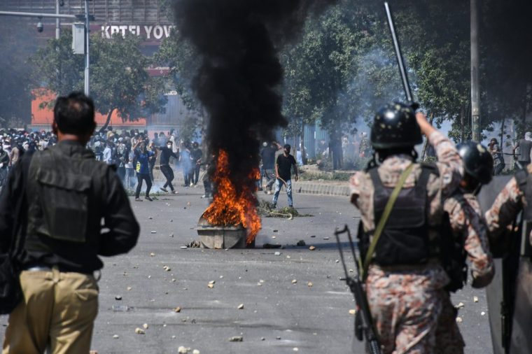 Shiite Muslims throw stones toward paramilitary soldiers and police officers during a protest to condemn the killing of Iranian Supreme Leader Ayatollah Ali Khamenei, at near the U.S. Consulate in Karachi, Pakistan, Sunday, March 1, 2026. (AP Photo/Ali Raza)