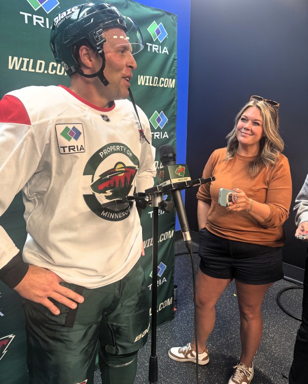 Jessi Pierce smiles as she listens to Jack Johnson speak into a microphone.