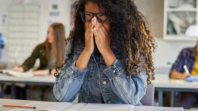 Tired young adult sitting at a desk in a classroom