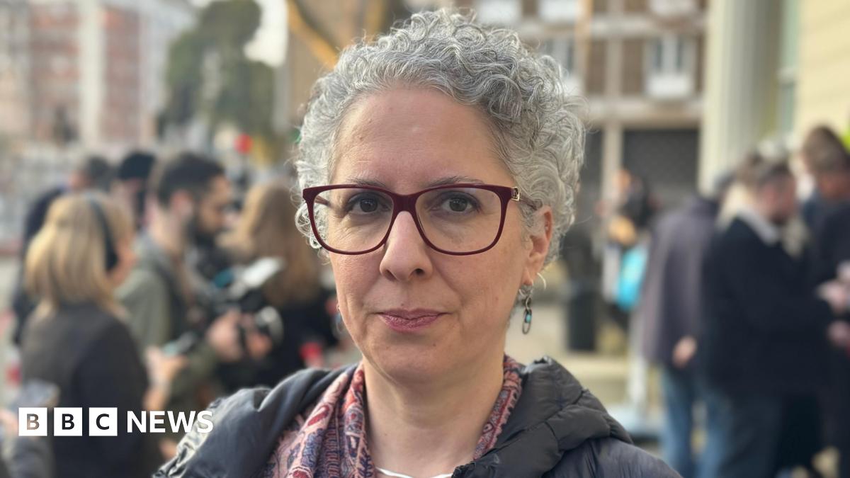 A nurse or medical practitioner wearing gloves and holding a Covid test. Behind her is a an extract of a handwritten document with words highlighted saying: "To stop NHS collapse".