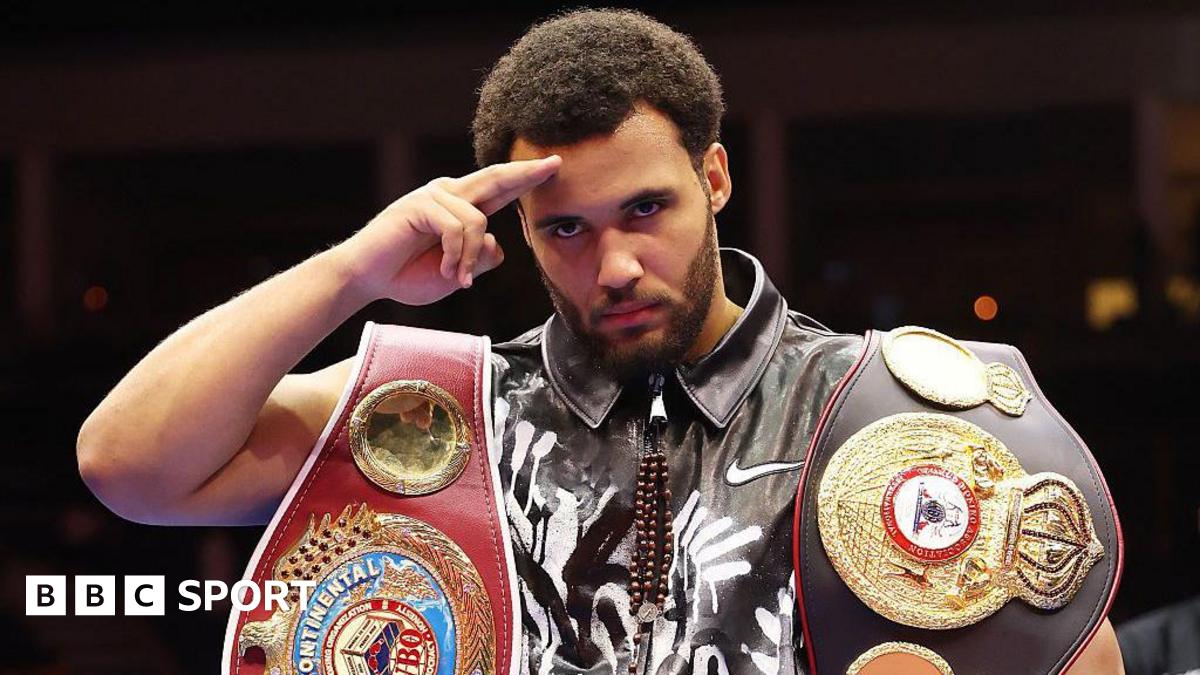 Moses Itauma salutes the camera with his belts around his shoulders