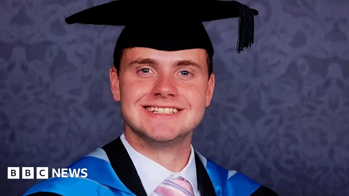 Jack O'Sullivan pictured in his blue graduation robes, wearing a black mortar board and smiling at the camera.