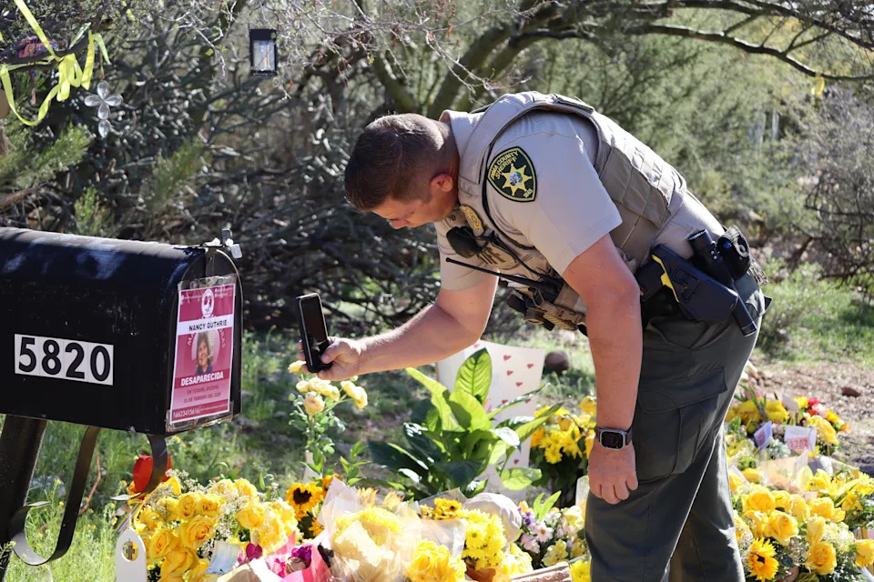 A law enforcement officer from the Pima County Sheriff's Department photographs a flyer on a mailbox at the home of Nancy Guthrie in Tucson, Ariz.