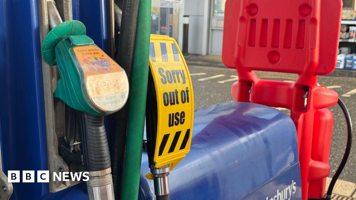 A 'sorry out of use' sign over a fuel pump in a supermarket forecourt