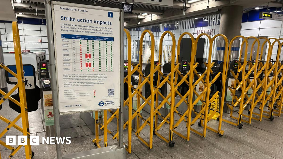 Yellow barriers pulled across ticket barriers with a notice board displaying info under a 'strike action impacts' banner