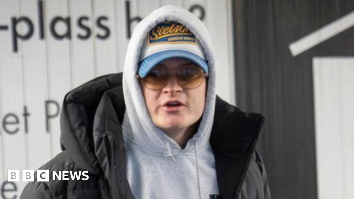 Sturla Henriksboe (R) wearing a black gown over a white shirt and patterned blue and lilac tie stands in front of a microphone as police prosecutor Andreas Kruszewski sit alongside to his right, his head shaved, sporting a black beard and wearing glasses