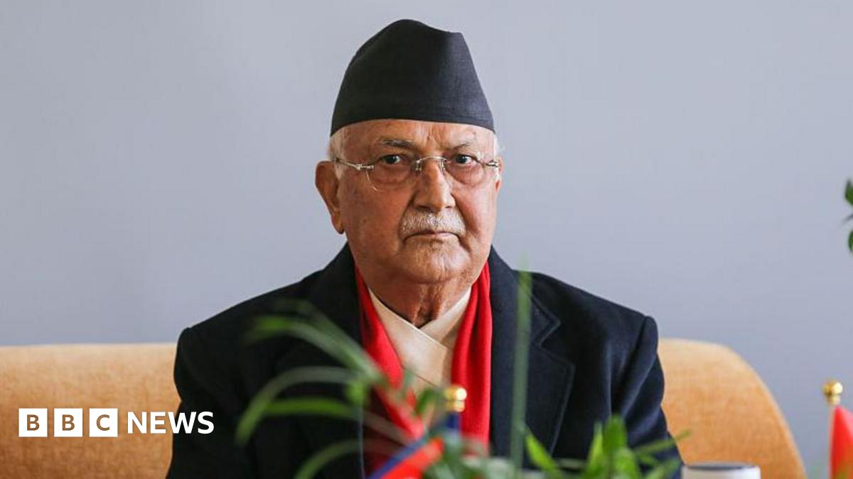 A man wearing  a black suit and black hat looks at the camera