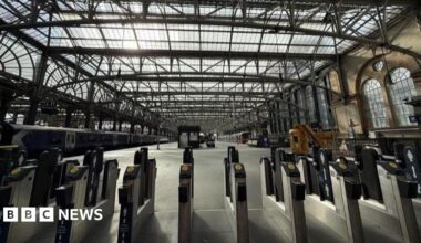 The inside of Glasgow Central Station showing train platforms and ticket barriers.