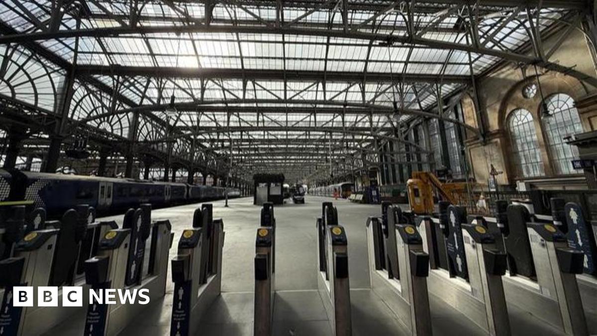 The inside of Glasgow Central Station showing train platforms and ticket barriers.