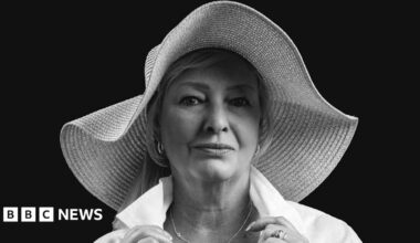 A professional black and white photo of a middle-aged woman in a wide-brimmed sunhat and a white shirt