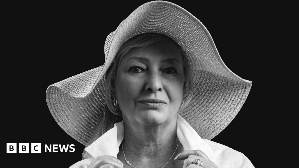 A professional black and white photo of a middle-aged woman in a wide-brimmed sunhat and a white shirt