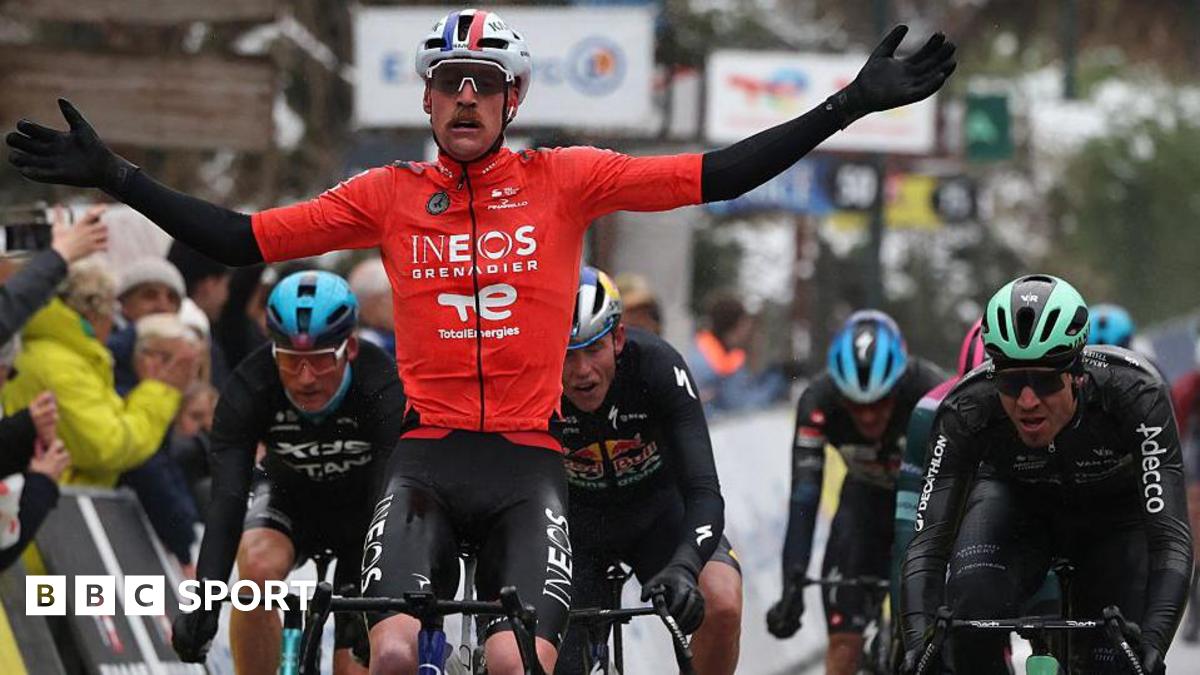 Dorian Godon holds out his arms as he rides his bicycle next to several other competitors