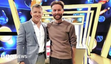 Publicity image of Ben Shephard and Jamie posing together on the Tipping Poin set, which has a blue background and a row of yellow square arches above.