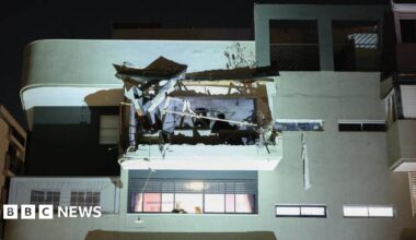 A first responder gazes upwards at the site of a cluster bomb strike.