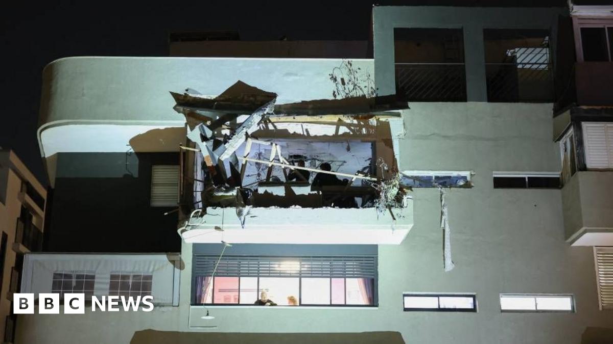 A first responder gazes upwards at the site of a cluster bomb strike.