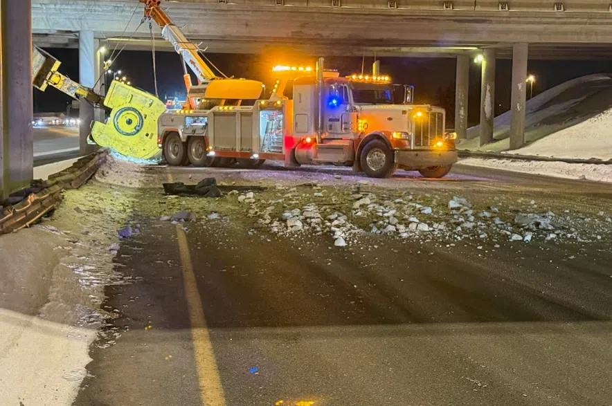City crews clean up the aftermath of a semi-truck hauling equipment crashed into the Highway 11 overpass.