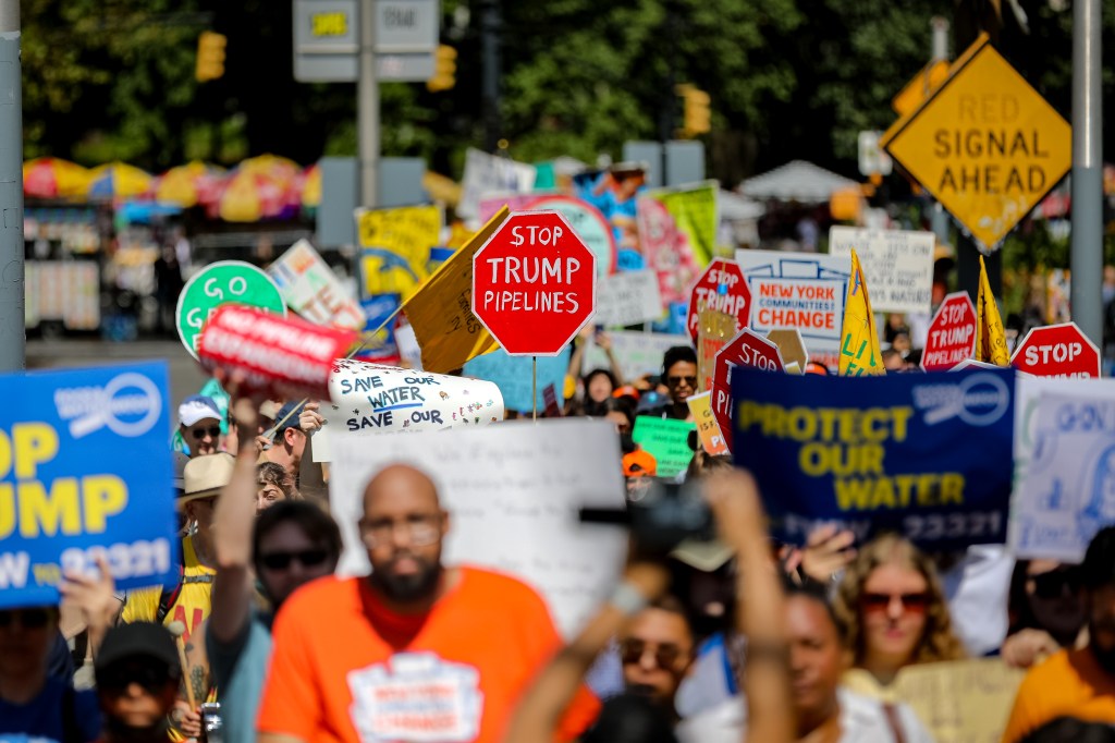 Climate activists marching with signs saying "Stop Trump Pipelines" and "Protect Our Water."