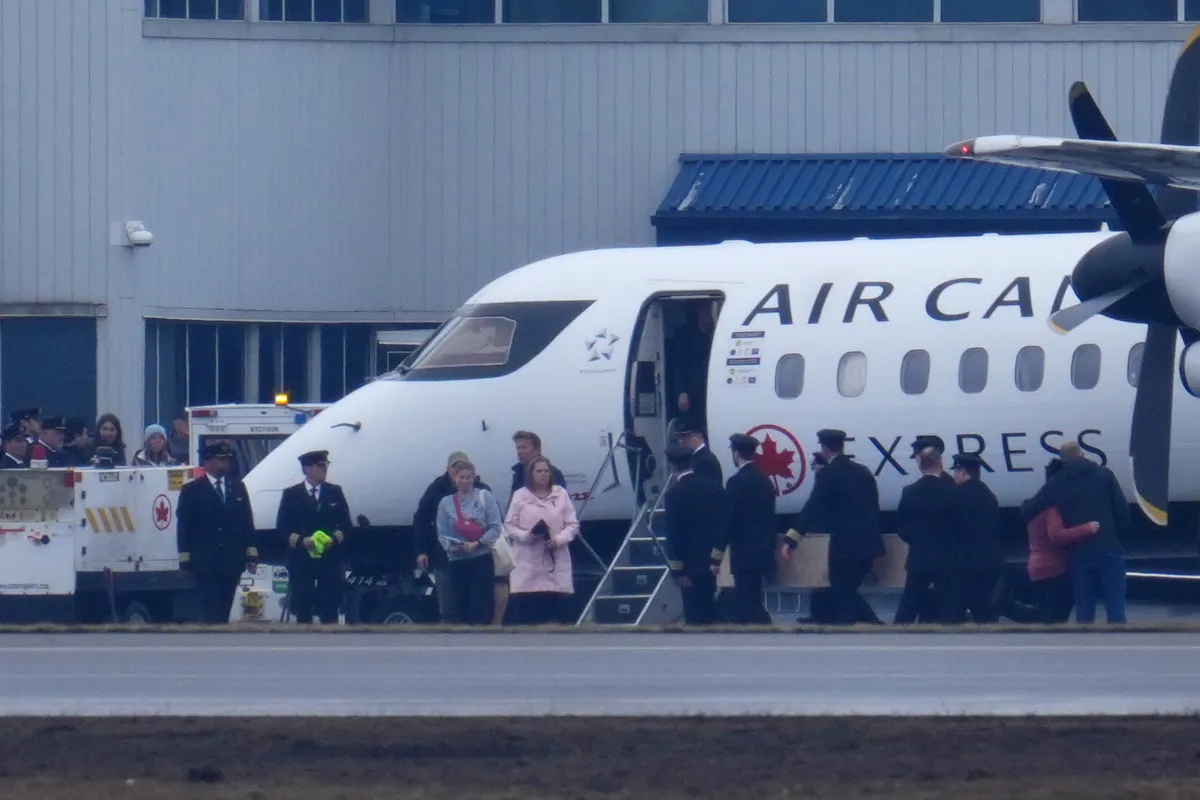 Pilots in uniform carry a casket next to an Air Canada Express plane at an airport