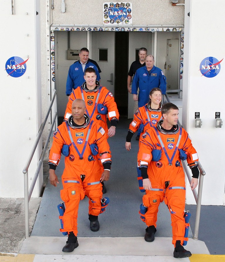 The four Artemis II lunar mission astronauts wearing gear, followed by operations crew, depart a building after the Countdown Demonstration Test.