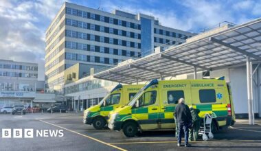 Ambulances parked outside a large white hospital building.