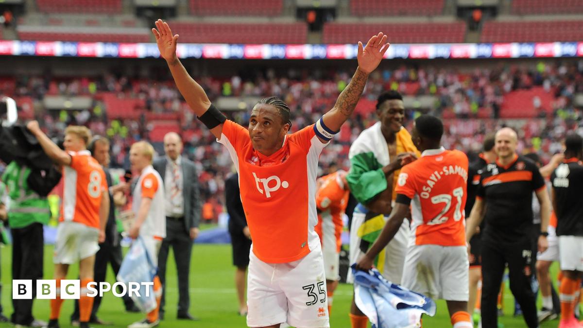 Neil Danns, while playing for Blackpool, celebrates to the fans with his arms out wide after his side's victory against Exeter City in the League Two play-off final at Wembley back in 2017.