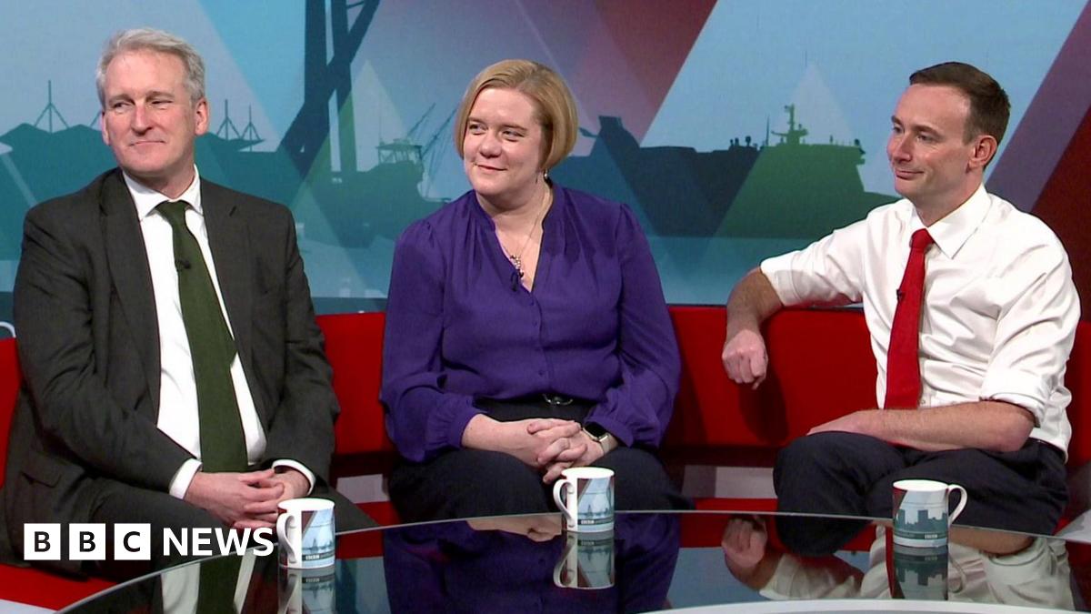 Damian Hinds, wearing a dark suit and green tie,  Zoe Franklin wearing a purple blouse and Tom Hayes wearing white shirt with sleeves rolled up on the a red TV studio sofa
