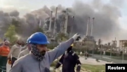 Workers evacuate the area around Saudi Aramco's Ras Tanura oil refinery as smoke rises following a reported Iranian drone strike on March 2.
