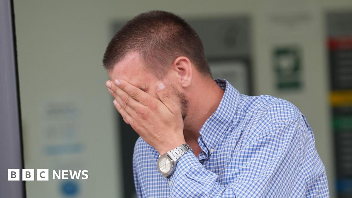 Shaun Thompson, who is wearing a blue and white checkered shirt, covering his face as he leaves court. He has short brown hair.