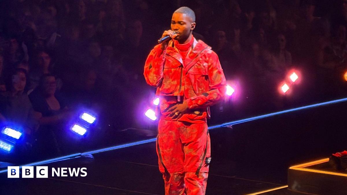 Dave performing with a microphone, wearing a red outfit