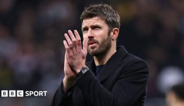 Michael Carrick, in a dark coat, applauds Manchester United fans