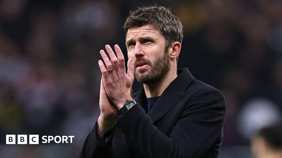 Michael Carrick, in a dark coat, applauds Manchester United fans
