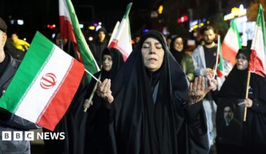 People wave national flags and hold portraits of Iran's supreme leader Mojtaba Khamenei as they march in support of the Iranian armed forces in central Tehran on March 25, 2026.